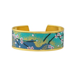 Brass cuff bracelet and cherry blossoms on a blue background