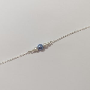 Puede incluir: Un brazalete de cadena de plata con cuentas de perlas blancas y azules.