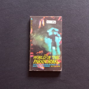 May include: A vintage paperback book cover with a blue and green abstract design. The title is "The World of the Paranormal" and the subtitle is "The realities, revelations and riddles of the realm of psychic experience." The author is Walter McGraw.