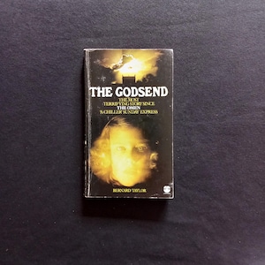 May include: A paperback book titled "The Godsend" with a yellow and orange cover featuring a woman's face. The book's subtitle is "The most terrifying story since The Omen - A Chiller Sunday Express".