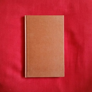 Puede incluir: Un libro de tapa dura marrón con una cubierta lisa.