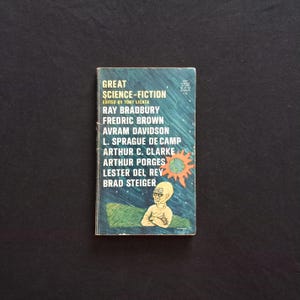May include: A vintage paperback book titled "Great Science-Fiction" edited by Tony Licata. The cover features a stylized illustration of an alien figure and a sun against a blue and green background. Authors include Ray Bradbury and Arthur C. Clarke.