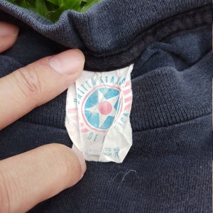 May include: A black t-shirt with a white tag that says "United States of America" with a red star in the center.