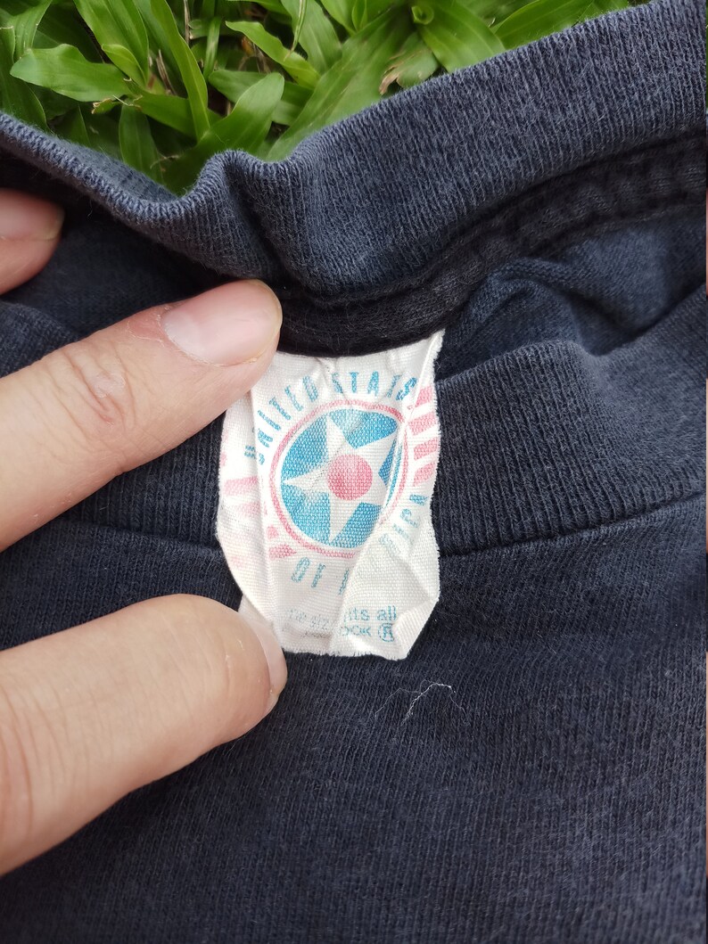 May include: A black t-shirt with a white tag that says "United States of America" with a red star in the center.