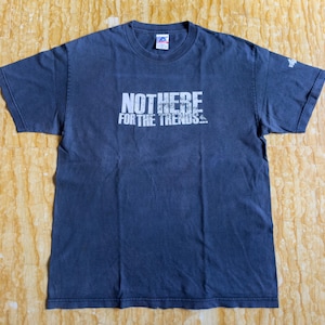 以下が含まれることがあります： 前面に白い文字で「NOT HERE FOR THE TRENDS... 」とプリントされた濃い青色のTシャツです。