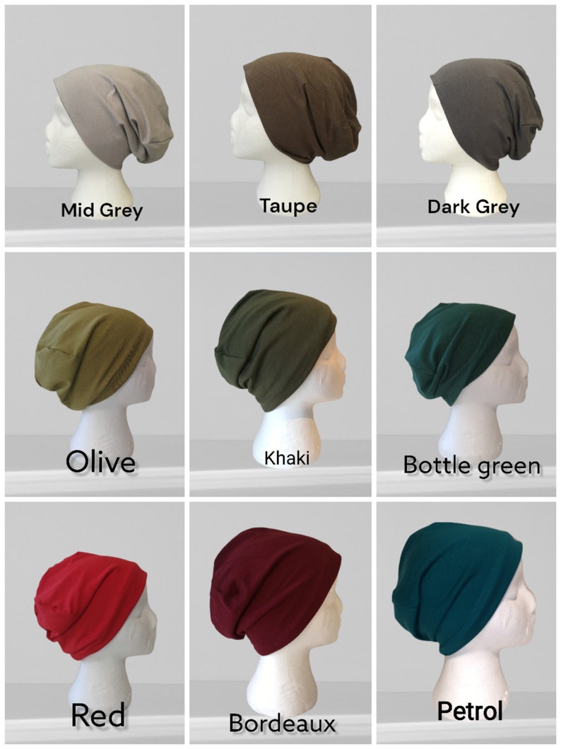 May include: A collection of nine solid-colored beanies displayed on mannequin heads. Colors include mid-grey, taupe, dark grey, olive, khaki, bottle green, red, bordeaux, and petrol. Each beanie is a different shade.