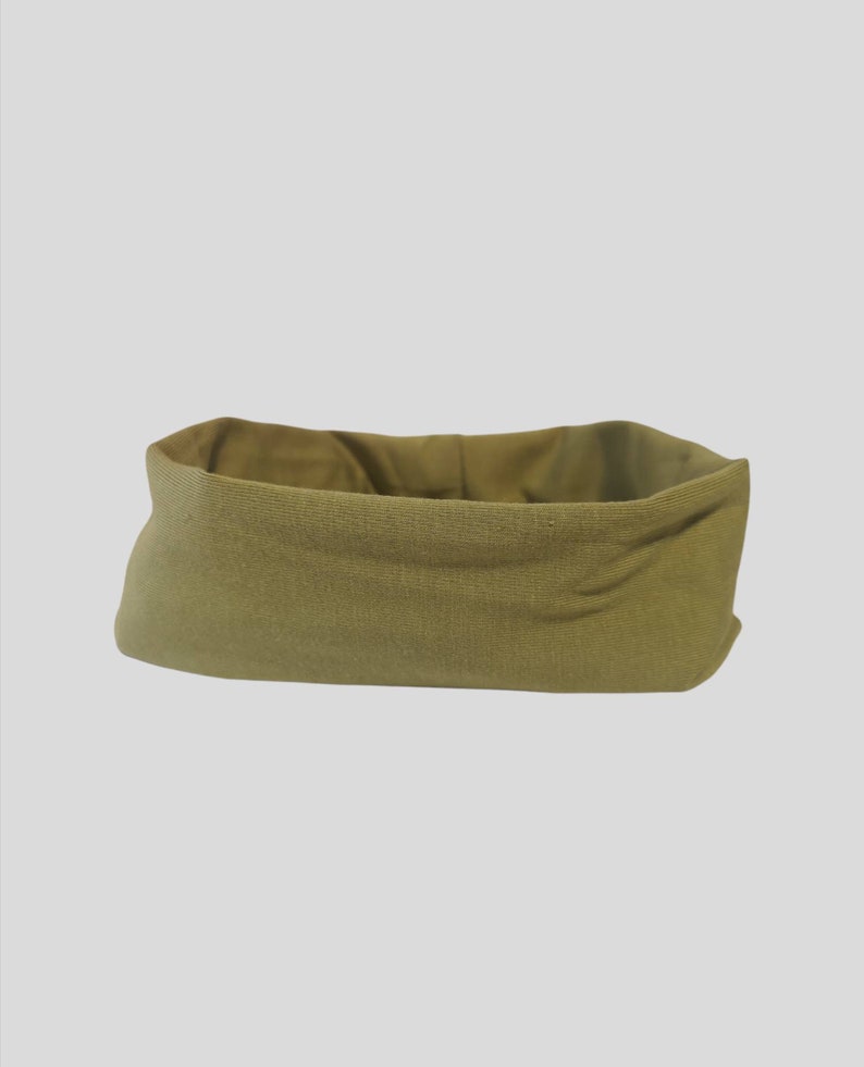 May include: A rectangular, olive green fabric basket with a folded-over top. The basket has a textured appearance and a neutral color, suitable for various storage purposes. The interior is a lighter shade of olive green.