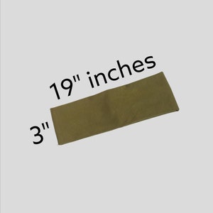 May include: A rectangular, olive-green fabric item, measuring 19 inches long and 3 inches wide, is displayed against a light gray background. The dimensions are clearly labeled with black text. The item appears to be a piece of fabric.