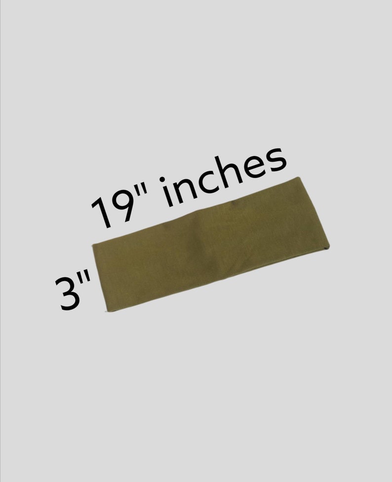 May include: A rectangular, olive-green fabric item, measuring 19 inches long and 3 inches wide, is displayed against a light gray background. The dimensions are clearly labeled with black text. The item appears to be a piece of fabric.