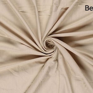 May include: Beige fabric with a swirling pattern. The fabric is a light tan color, with the word "Beige" in the upper right corner. The fabric is folded and draped, creating a spiral effect in the center.