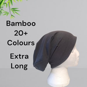 May include: A dark grey, extra-long bamboo beanie is shown on a white mannequin head. The image includes the text "Bamboo 20+ Colours Extra Long". The beanie is made of a soft, stretchy material.