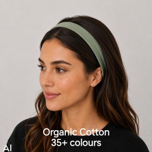 May include: A solid sage green headband made of organic cotton. The headband features a smooth, matte fabric finish and a simple, wide band design. The text on the image reads Organic Cotton 35+ colours, indicating the material and variety.