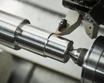 May include: Close-up of a metal rod being machined on a lathe. The cutting tool is visible, and the metal shavings are flying off the rod.