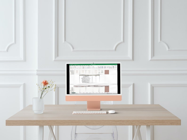 Op de afbeelding: Een roze gouden iMac-computer met een wit toetsenbord en muis op een licht houten bureau. Het computerscherm toont een spreadsheet met gegevens en grafieken.
