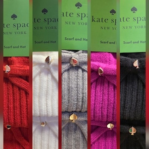 May include: A display of five Kate Spade scarf and hat sets in various colors: red, white, gray, magenta, and black. Each set is labeled with a number and features a gold-toned spade-shaped accent.