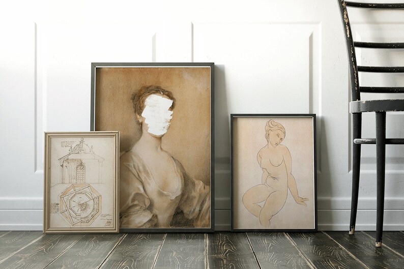May include: Three framed drawings on a wooden floor. The drawing on the left is a black and white architectural design. The drawing in the center is a sepia toned portrait of a woman with her face obscured by white paint. The drawing on the right is a sepia toned sketch of a nude woman sitting down.