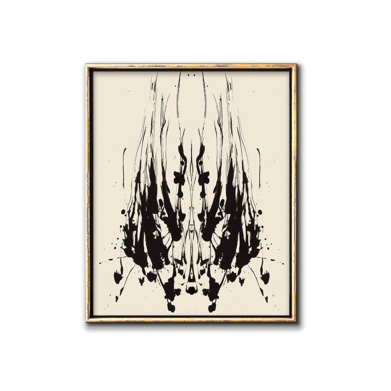 May include: A black and white abstract inkblot print in a gold frame. The inkblot is symmetrical and resembles a stylized human figure.