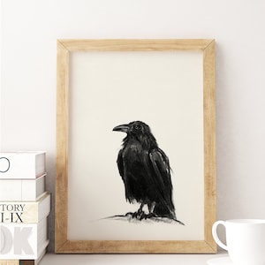 May include: A black and white drawing of a raven perched on a branch. The raven is facing to the right and has a detailed, realistic appearance. The drawing is framed in a light wood frame.