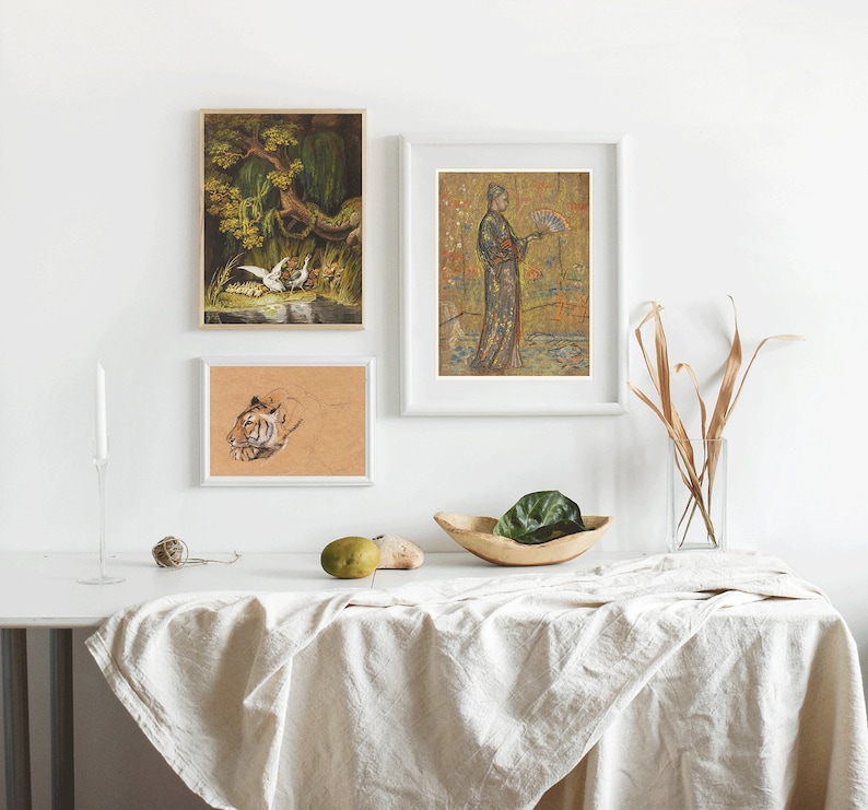 May include: Three framed prints on a white wall above a white table with a linen tablecloth. The prints are of a tiger, a woman in a kimono, and a bird in a tree.