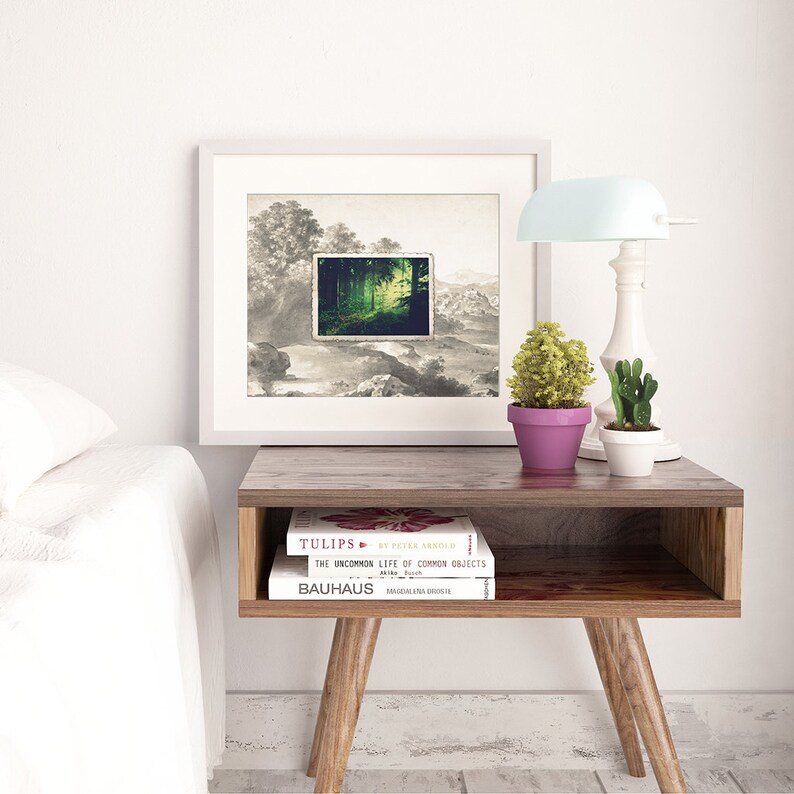 Puede incluir: Una imagen enmarcada en blanco con una imagen de paisaje en blanco y negro con una escena de bosque verde dentro de un marco m&aacute;s peque&ntilde;o. La imagen est&aacute; sobre una mesa auxiliar de madera con dos libros apilados uno encima del otro. Los libros se titulan "Tulips" y "The Uncommon Life of Common Objects". Una l&aacute;mpara con una pantalla azul claro est&aacute; sobre la mesa junto a la imagen.