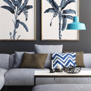May include: A gray sectional sofa with brown and blue patterned throw pillows, a white coffee table with a black metal frame, and a blue pendant light hanging above the sofa.