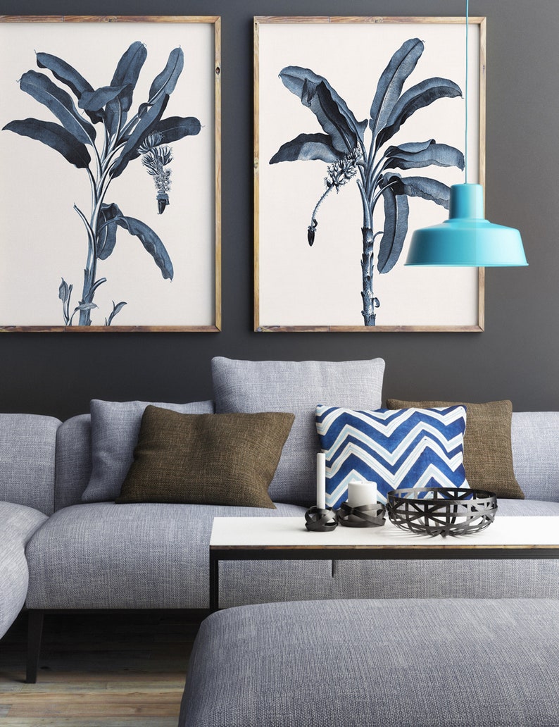 May include: A gray sectional sofa with brown and blue patterned throw pillows, a white coffee table with a black metal frame, and a blue pendant light hanging above the sofa.