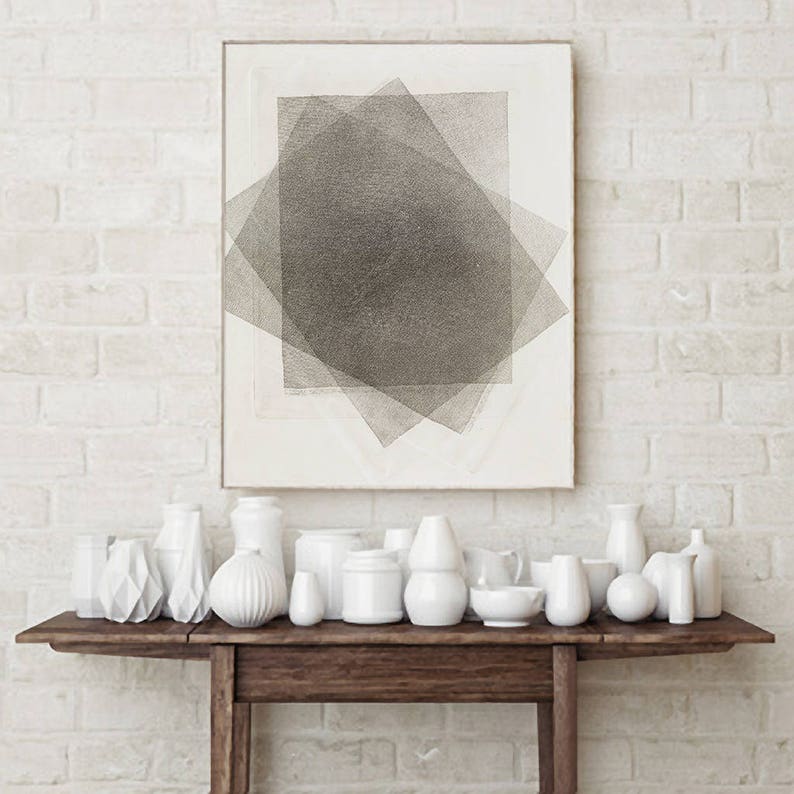 Pu&ograve; includere: Una collezione di vasi e oggetti decorativi in ceramica bianca di varie forme e dimensioni esposti su un tavolo in legno scuro. Sopra, una stampa astratta incorniciata con forme geometriche grigie sovrapposte su sfondo bianco. Il muro &egrave; fatto di mattoni bianchi.