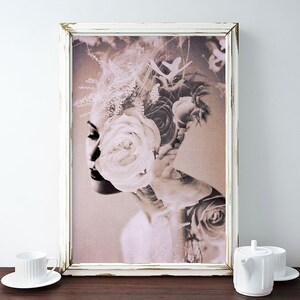 May include: A sepia-toned photograph of a woman's face with a large white rose covering her eye. The woman's face is partially obscured by the rose and other flowers. The image is framed in a white frame.