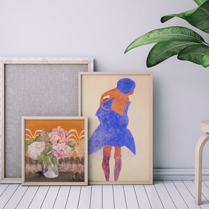 May include: Three framed art prints, one with a floral still life, one with a woman in a blue dress, and one with a textured background.