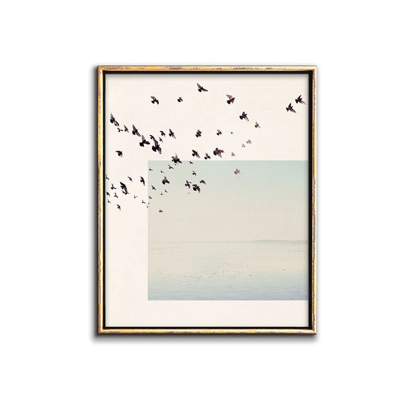 May include: A framed print of a flock of birds flying over a light blue and white landscape. The birds are black and the landscape is a soft, muted color.