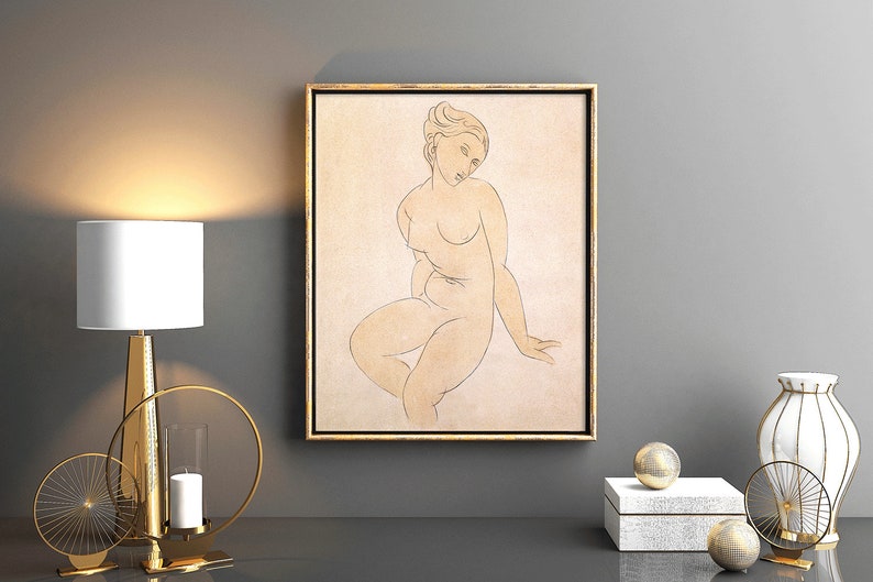 May include: A framed line drawing of a nude woman in a seated pose. The drawing is in shades of brown and beige on a cream background. The frame is gold.