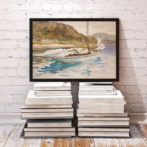 May include: A framed watercolor painting of a sailboat with white sails on a body of water. The boat is anchored in the water with mountains in the background. The painting is on a white brick wall with a stack of books on either side.
