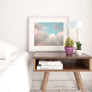 May include: A white bedside table with a wooden top and legs. There are three books stacked on the table, with the top book titled "Tulips: An Ever-Present Family". A small potted plant and a lamp are on the table.