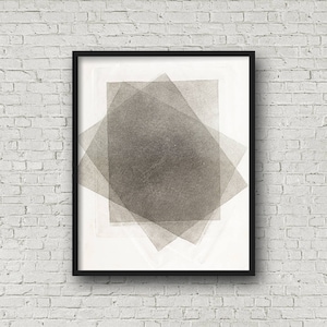 Pu&ograve; includere: Stampa d'arte astratta in una cornice nera. L'opera presenta forme geometriche sovrapposte in tonalit&agrave; di grigio, creando un effetto a strati. La stampa &egrave; esposta su uno sfondo bianco e un muro di mattoni bianchi.