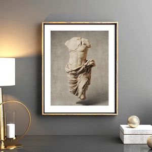 Pu&ograve; includere: Una stampa incorniciata di una scultura in marmo bianco di un torso con un panno drappeggiato. La scultura &egrave; su uno sfondo beige. La cornice &egrave; dorata.
