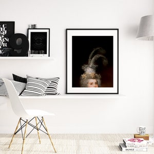 May include: A framed portrait of a person with a white wig and ornate headpiece, featuring feathers and gold accents. The artwork is displayed on a white wall, alongside other framed art and decorative items, creating a sophisticated interior design.