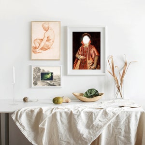 Puede incluir: Tres cuadros enmarcados en una pared blanca sobre una mesa blanca con un mantel blanco. Los cuadros son de un dibujo de un hombre desnudo, una pintura de una persona con una t&uacute;nica roja y la cara blanca, y una escena de paisaje.