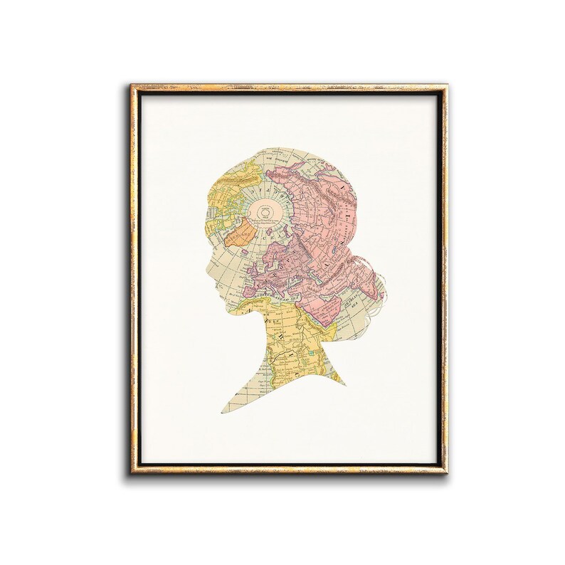 May include: A framed print of a woman's silhouette with a vintage world map overlay. The map is in shades of pink, yellow, and brown.