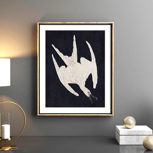 May include: A framed print of a white bird with its wings spread out against a dark blue background. The bird is depicted in a stylized, almost abstract manner.