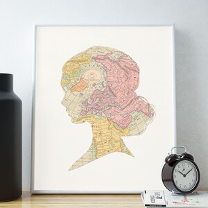 May include: A framed print of a vintage world map in a silhouette of a person's head. The map is in shades of pink, yellow, and blue. The print is on a white background.