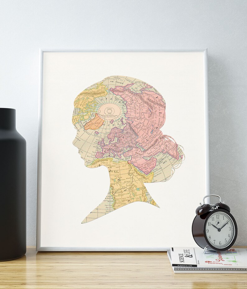 May include: A framed print of a vintage world map in a silhouette of a person's head. The map is in shades of pink, yellow, and blue. The print is on a white background.