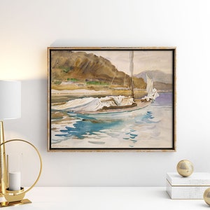 May include: A framed watercolor painting of a sailboat with white sails docked in a body of water. The water is a light blue color and the sky is a light gray color. The background of the painting is a mountain range.