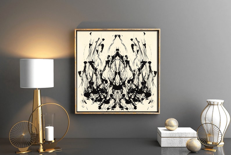 K&ouml;nnte beinhalten: Ein abstraktes Schwarzwei&szlig;bild in einem goldenen Rahmen h&auml;ngt an einer grauen Wand. Das Bild ist symmetrisch und zeigt eine Reihe von schwarzen Linien und Formen, die an eine Krone oder einen Baum erinnern. Das Bild ist von einem goldenen Rahmen umgeben und an einer grauen Wand ausgestellt.