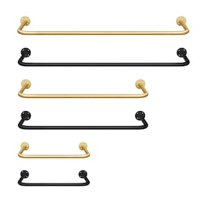 Könnte beinhalten: Eine Sammlung von Handtuchhaltern in Gold und Schwarz. Die Stangen sind gerade mit abgerundeten Enden und kreisförmigen Montageplatten. Die goldenen Stangen haben eine Messingoberfläche, während die schwarzen Stangen eine matte Oberfläche haben. Die Stangen sind in verschiedenen Längen erhältlich.