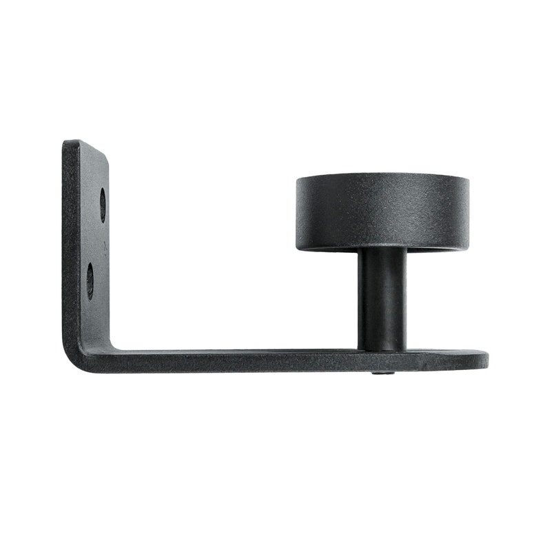 May include: Black metal barn door floor guide with a round base and a mounting bracket. The guide is designed to keep a barn door from swinging too far.