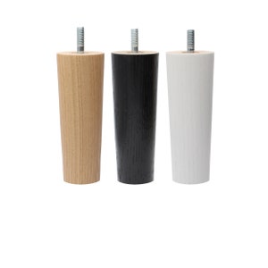 May include: Three wooden furniture legs in different colors: natural wood, black, and white. Each leg has a threaded metal screw at the top.