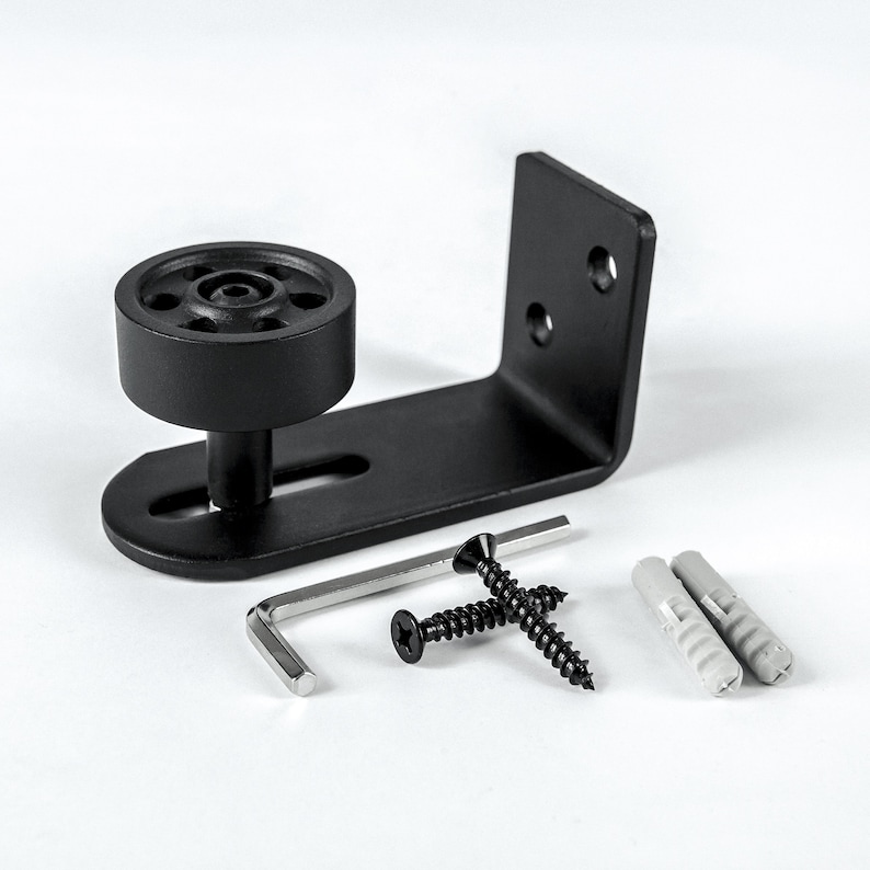 May include: Black metal door floor guide with a wheel, a hex wrench, two screws, and two plastic anchors.