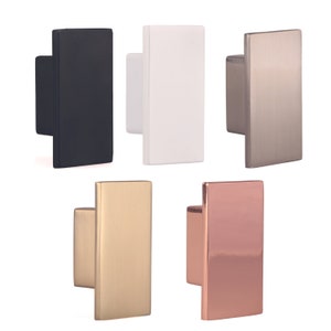 Può includere: Cinque pomelli rettangolari per armadi in diverse finiture: nero, bianco, nichel spazzolato, oro e oro rosa.