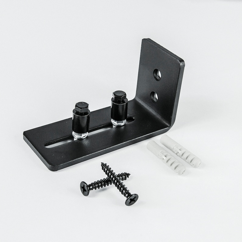 May include: Black metal sliding door hardware with two black screws and two white plastic anchors. The hardware has a metal bracket with two holes and a slot for the screws.