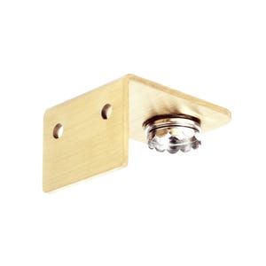 Op de afbeelding: Een gouden metalen beugel met twee gaten en een ronde, zilverkleurige dop met een gegolfde rand.